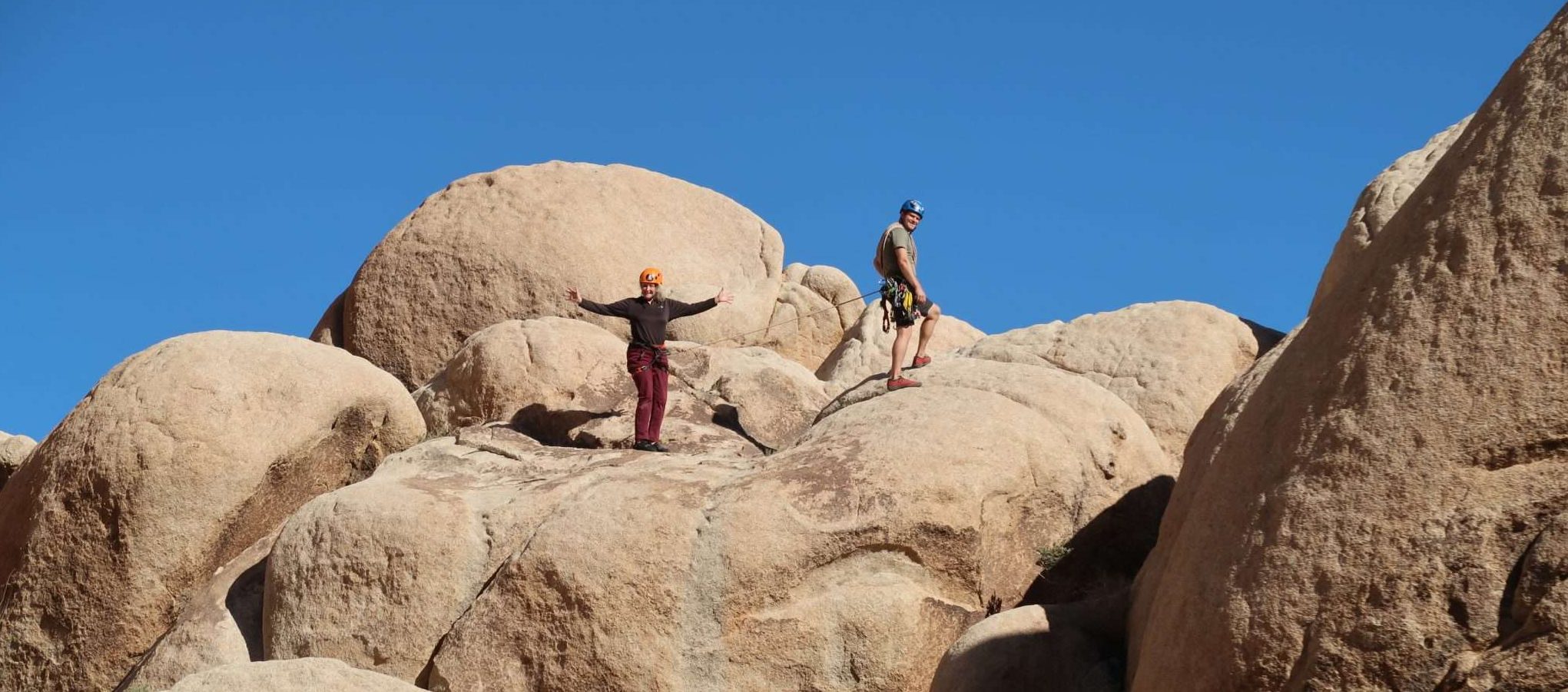 A client and a Cairn Leadership guide celebrating their accent of a large stack of boulders during a leadership development exercise.