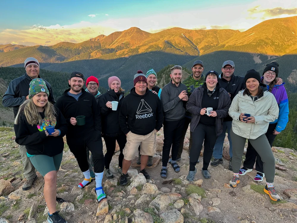A cheerful group of leaders-in-training enjoying a cup of warm coffee in the morning on a multi-day leadership development program with Cairn Leadership.
