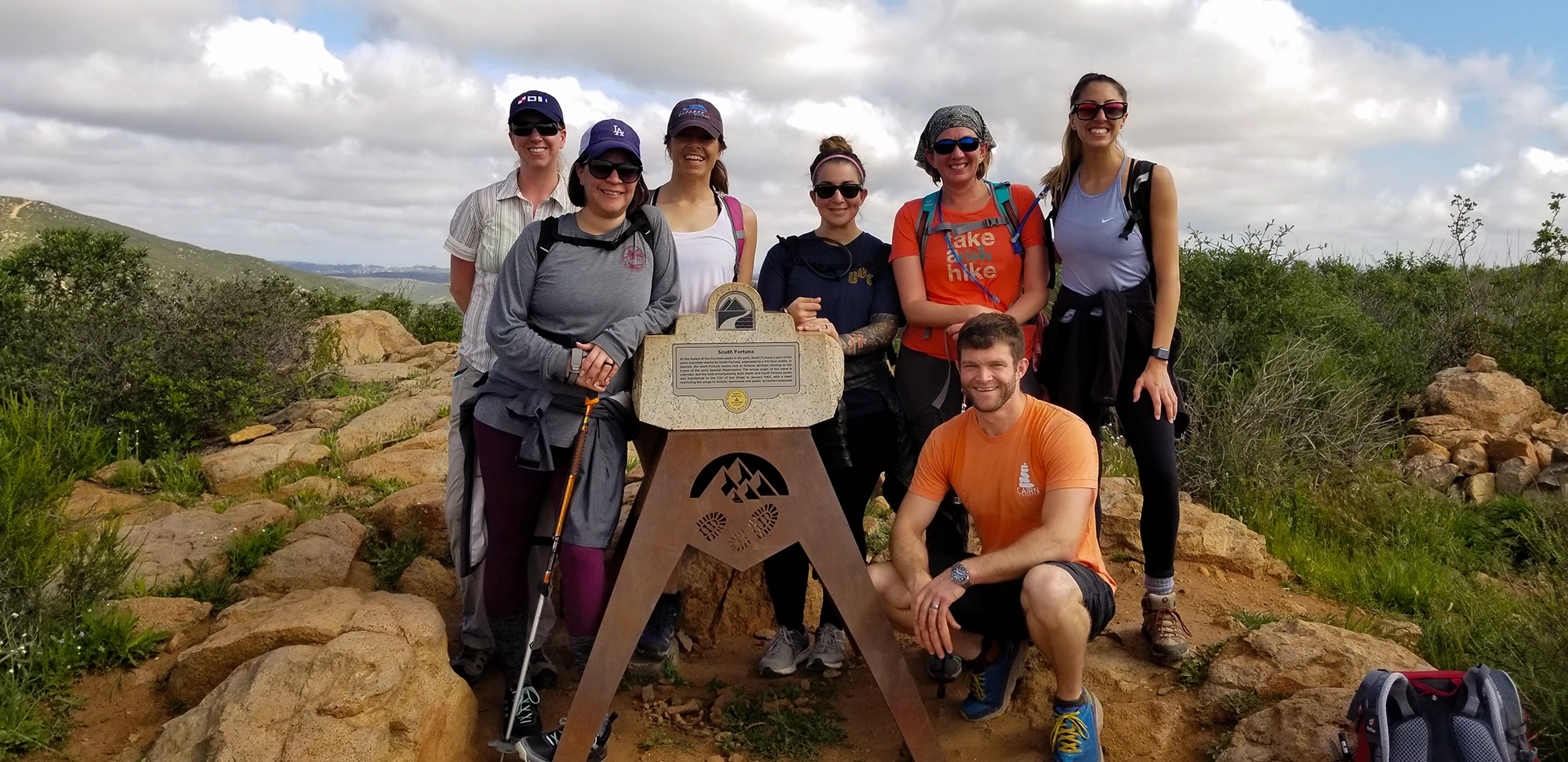 A group of clients smiling at the camera after reaching a stopping point on one of their team training programs with Cairn Leadership.