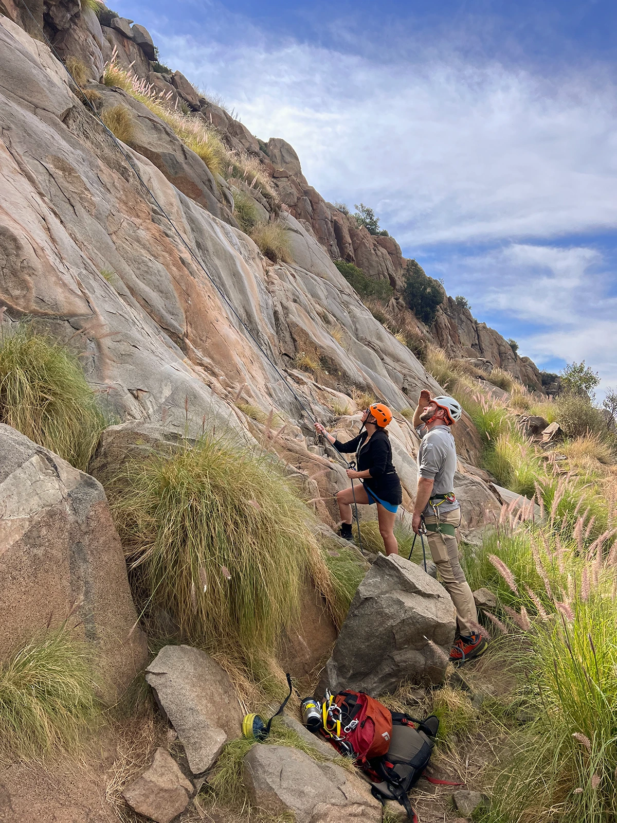 Cairn guide and one participant looking up the rock face, watching other climbers.