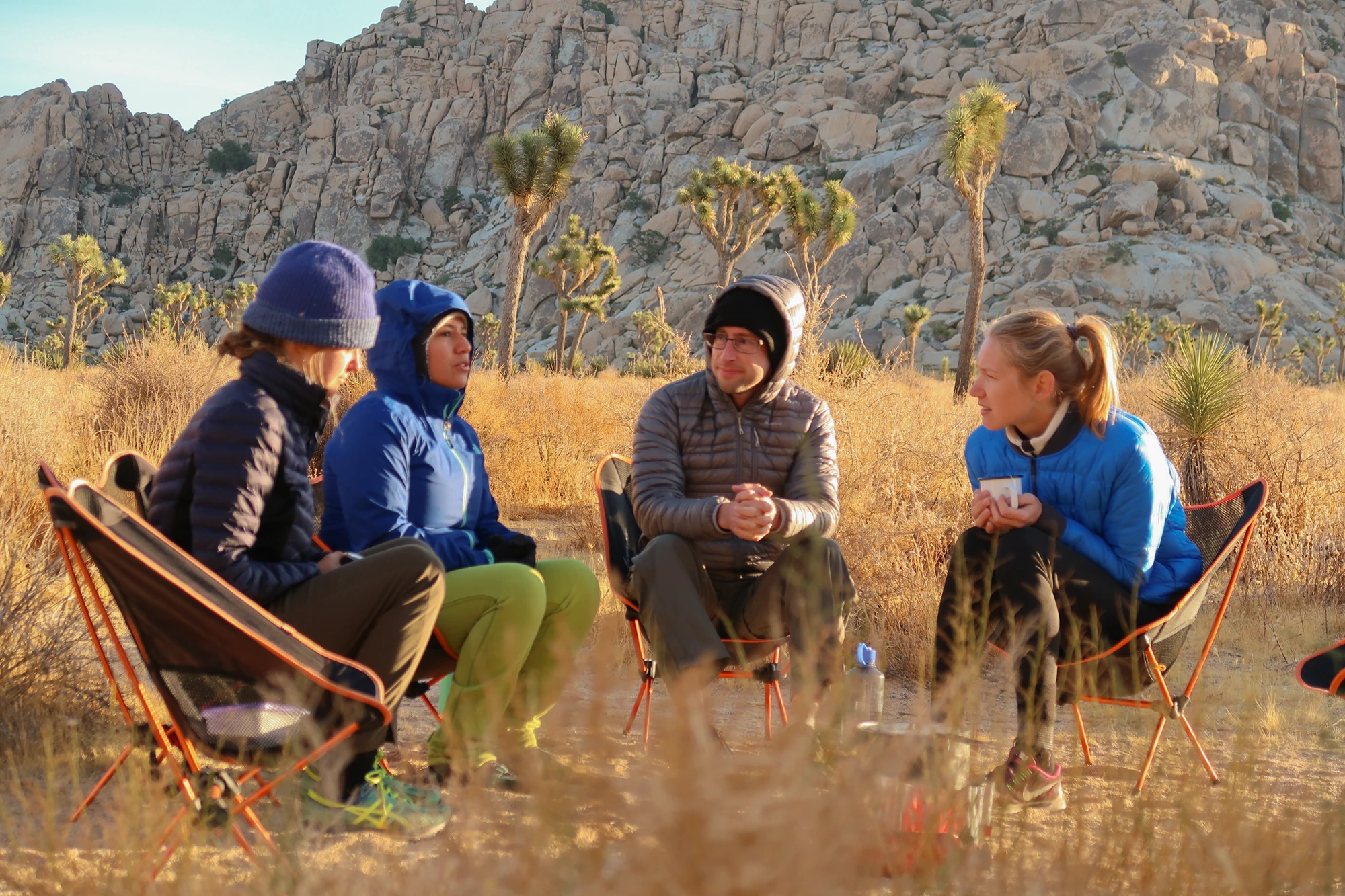 A close-up image of people sitting in camping chairs outside discussing leadership philosophies.