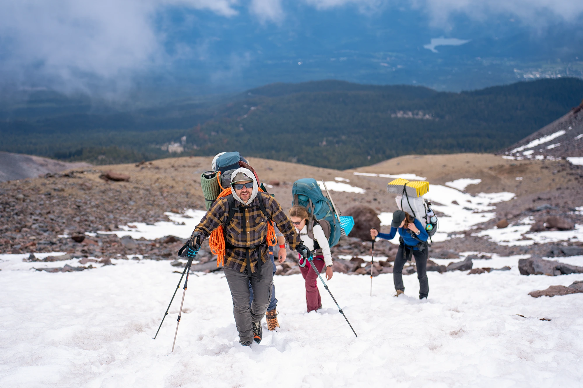 Cairn Leadership clients hiking up a snowy incline with a valley in the background.