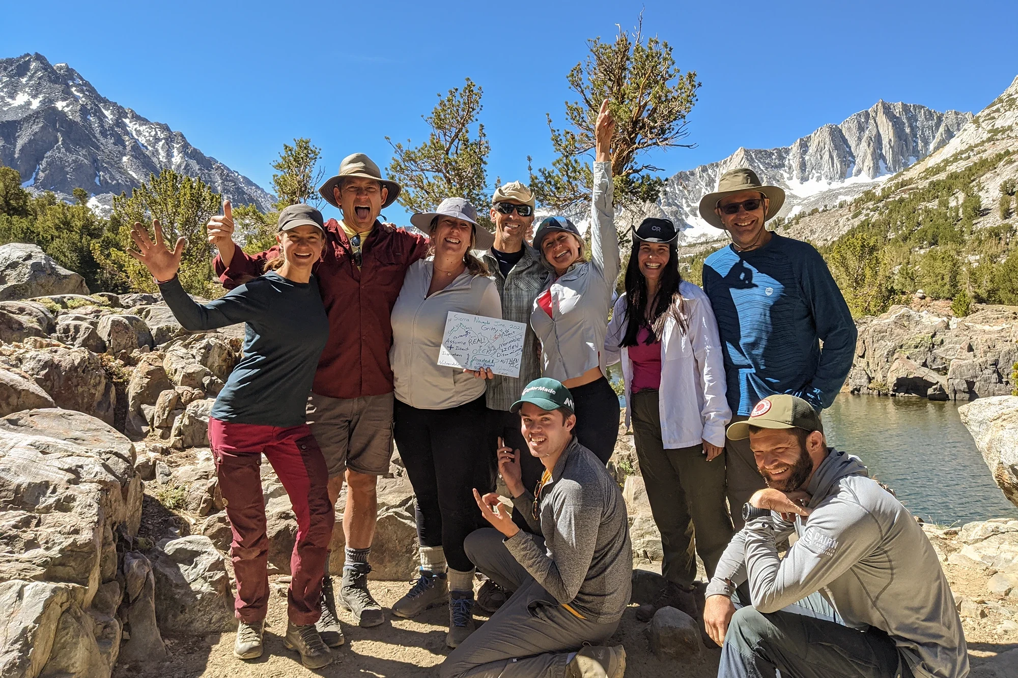 A happy group of Cairn Leadership clients new a small lake at the top of a mountain hike.