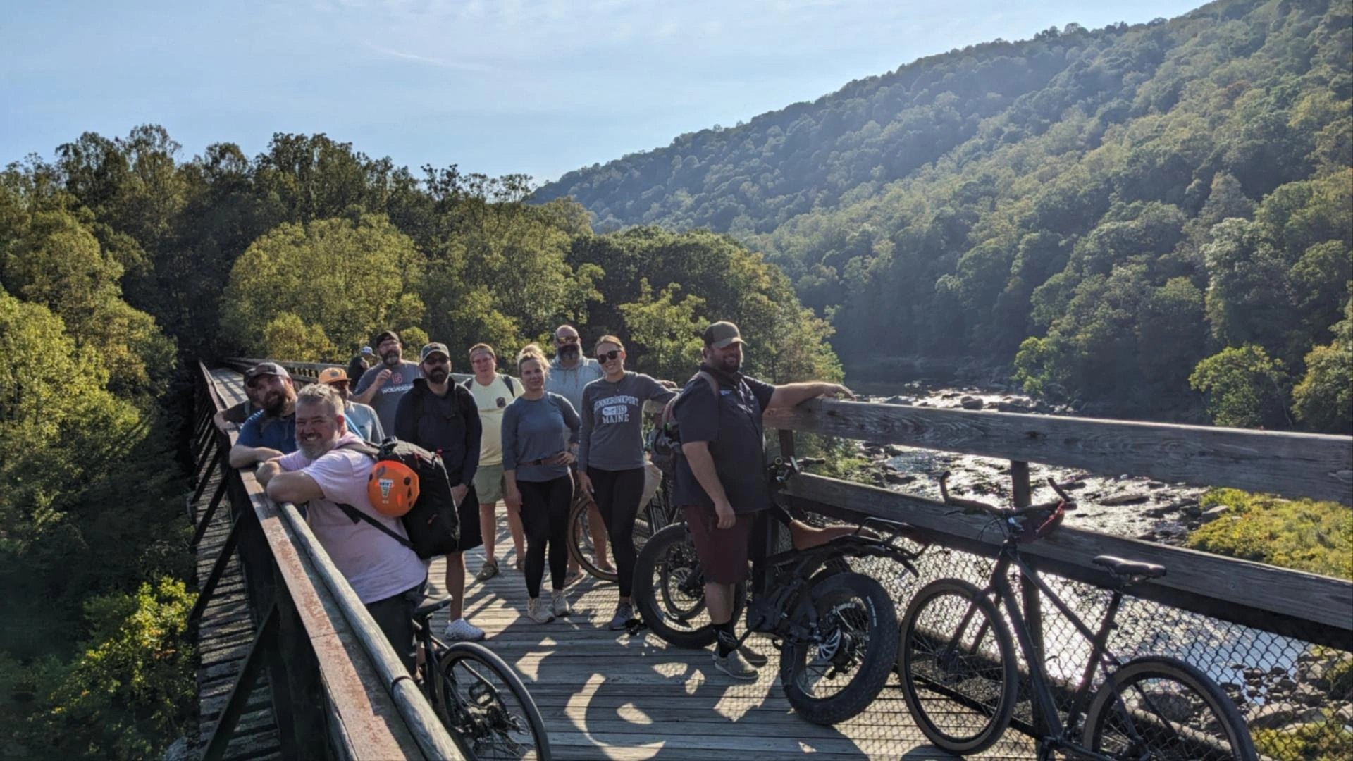 Cairn leadership clients on a corporate off-site training session stop at a scenic overlook on a wooden bridge while on a biking adventure
