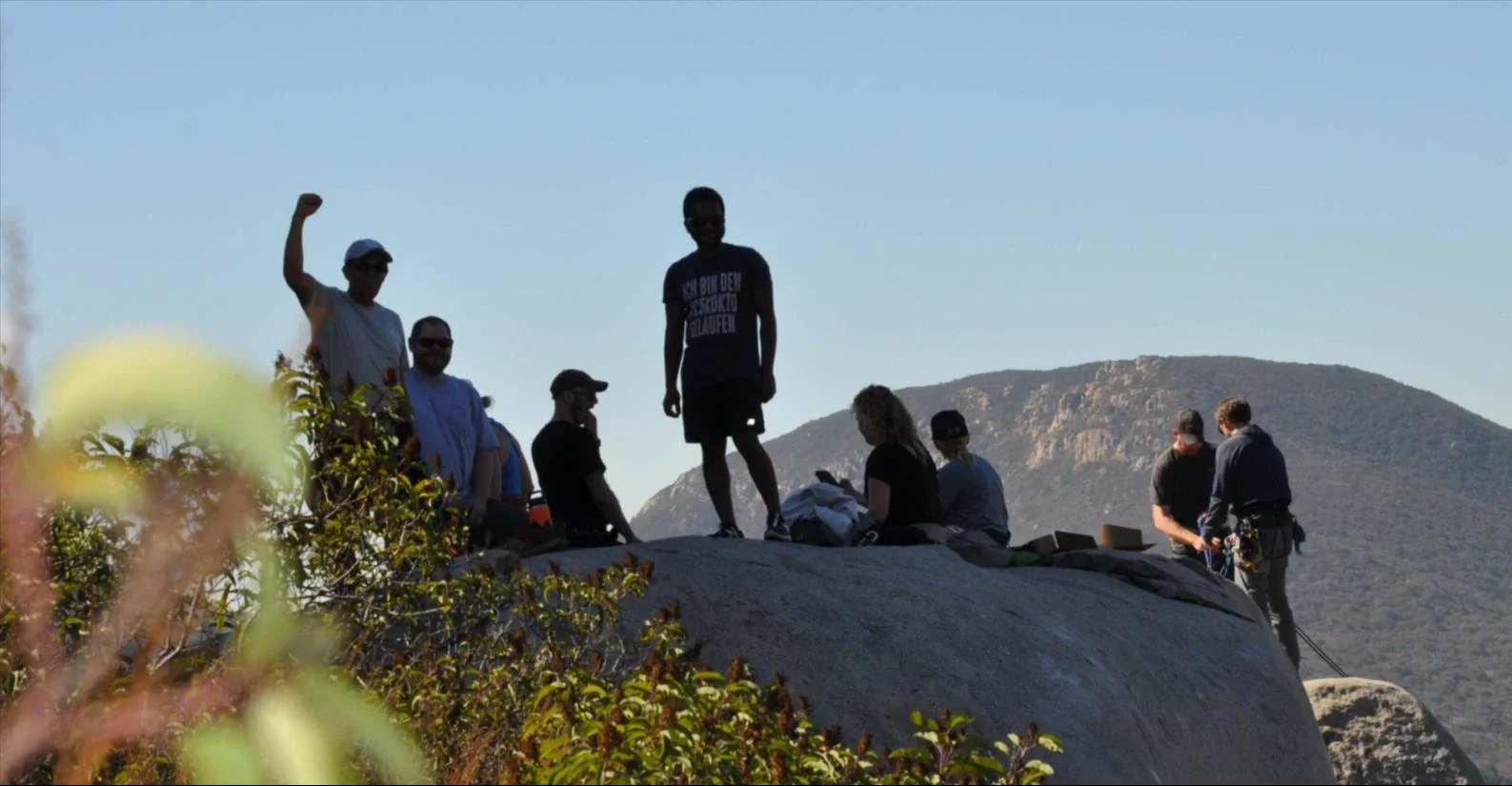 A remote team gatherson rock faces on a sunny day to rock climb and rappel together while fostering deep connections.