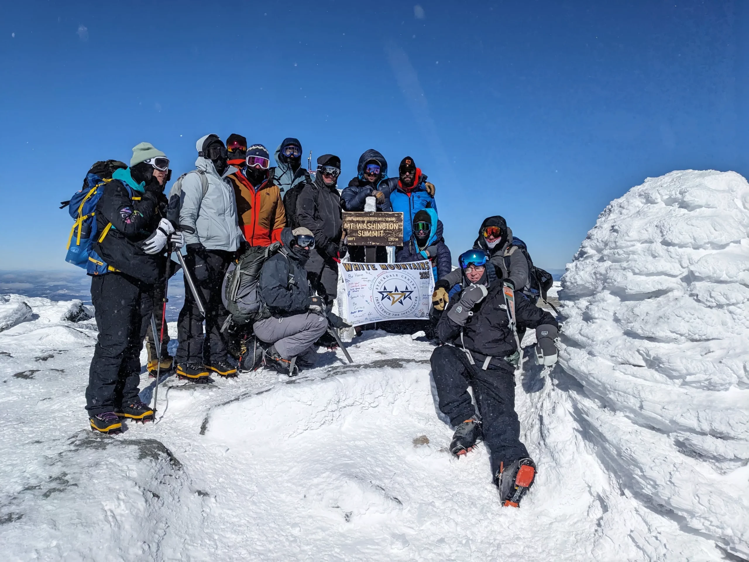 A group of climbers on a frozen mountain peak celebrate leading through uncertainty to reach the summit.